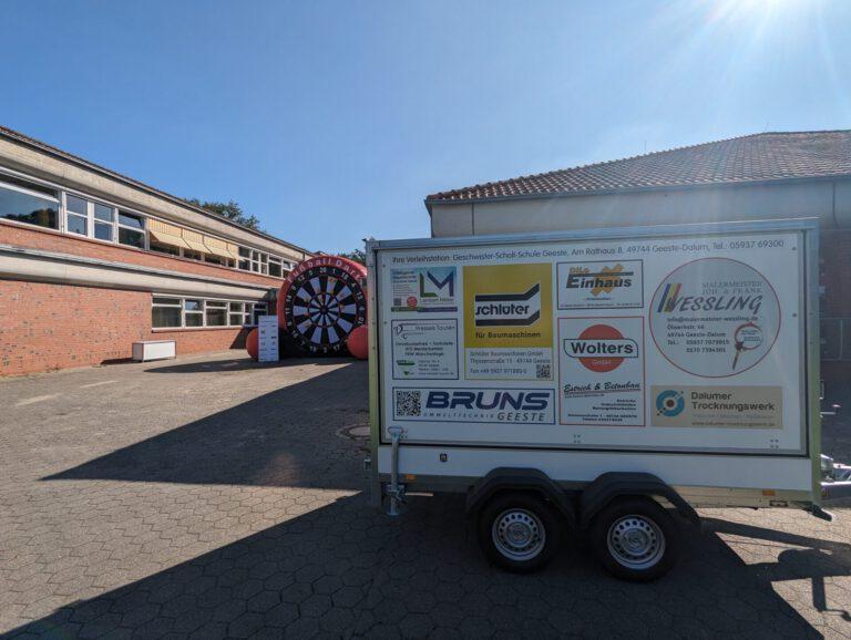Transportanhänger neben der Fußball-Dartscheibe auf dem Schulhof