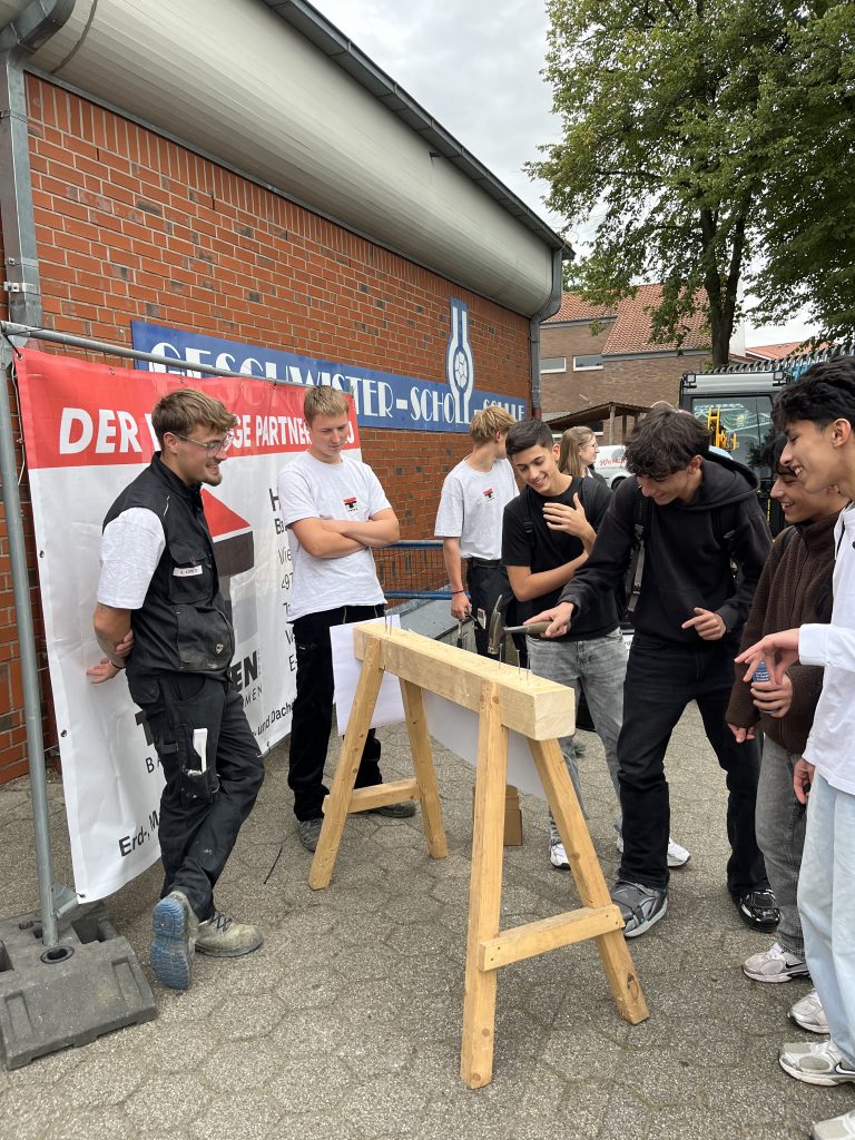 Jugendliche beim Hämmern an einem Holzgestell im Außenbereich.