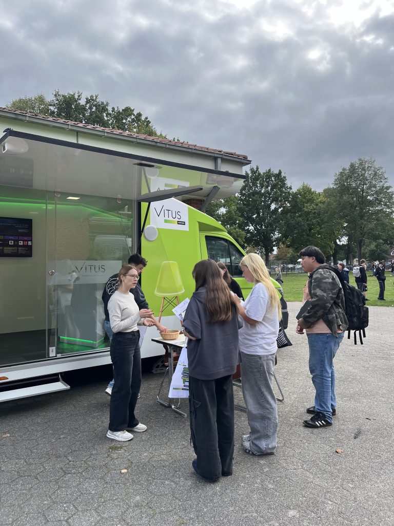 Jugendliche im Gespräch an einem mobilen Informationsstand im Außenbereich.
