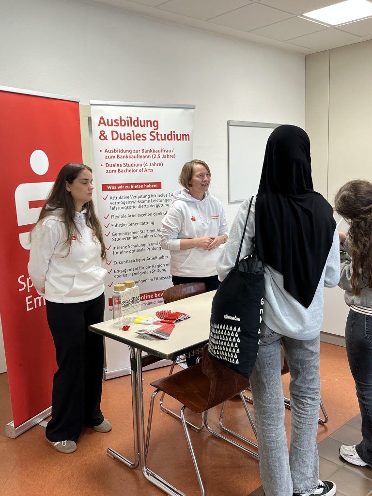 Jugendliche sprechen mit Mitarbeiterinnen an einem Stand zu Ausbildung und dualem Studium.