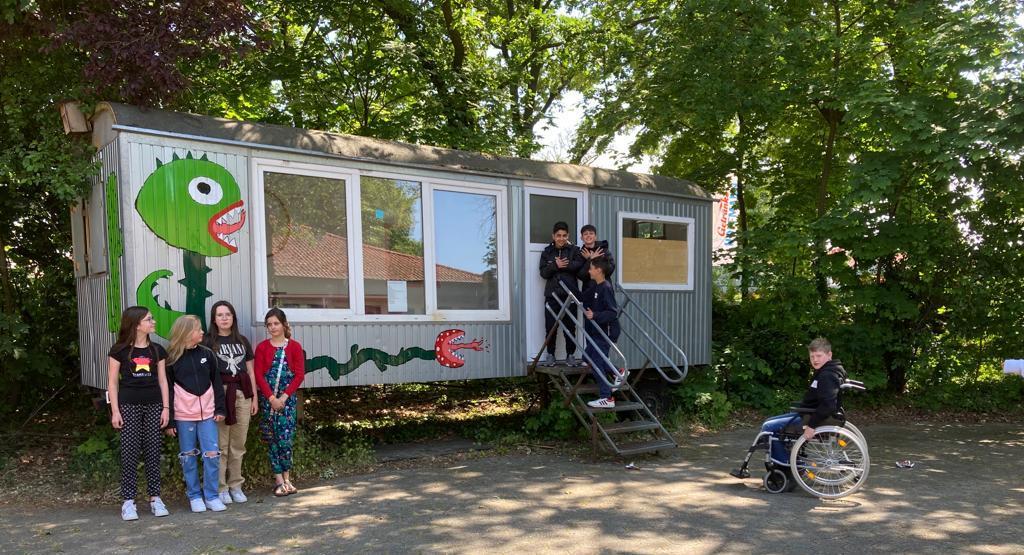 Kinder am Bauwagen für Spielgeräte auf dem Schulhof
